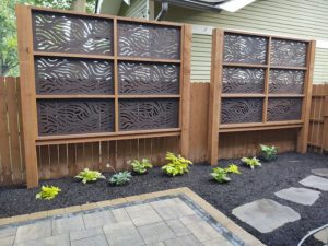 Brown decorative panels in front of privacy fence Capehart Landscape & Design